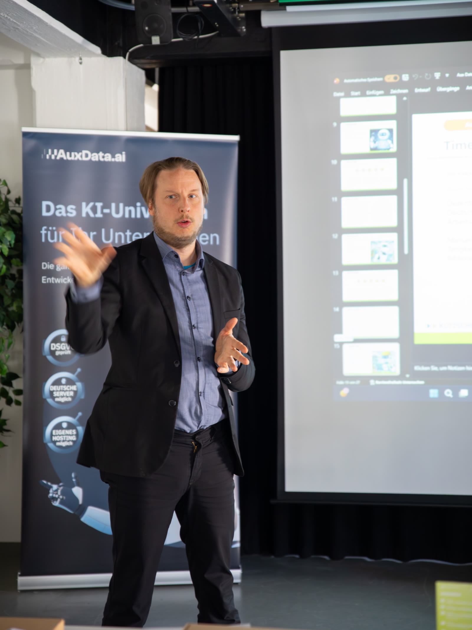 Florian Ludwig spricht über Auxdata bei einem KI-meets-BBQ-Event — Banner mit DSGVO-, Deutsche-Server- und Eigenes-Hosting-Badges im Hintergrund