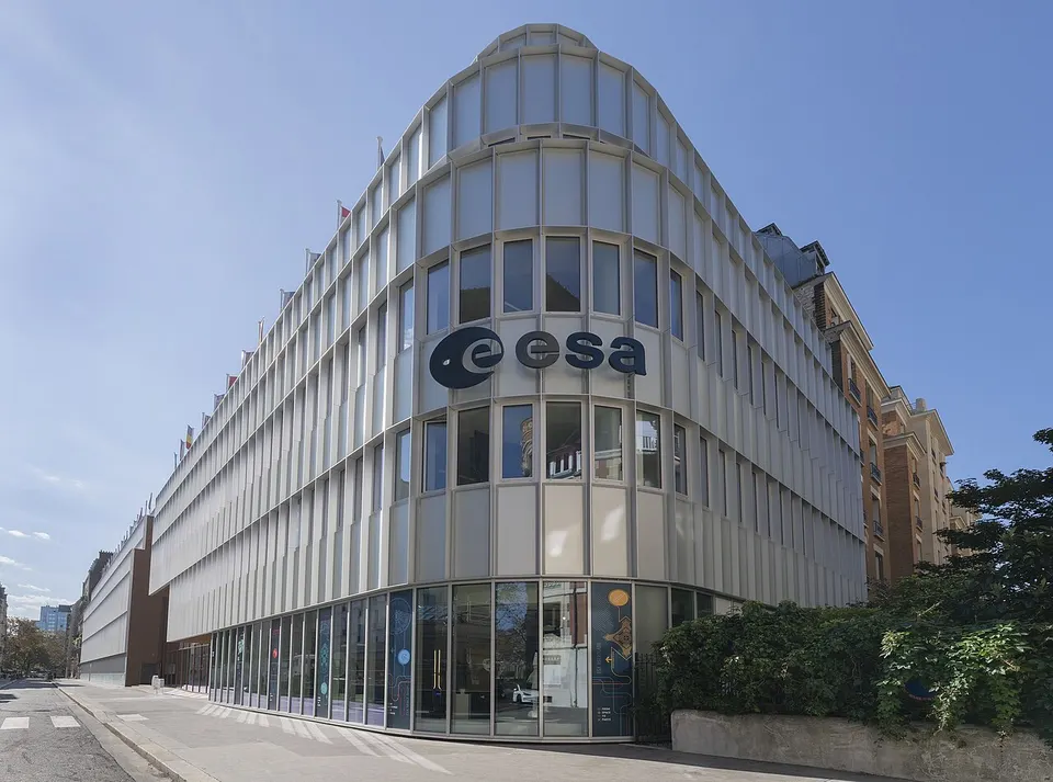 Geschwungenes helles Bürogebäude mit großem ESA-Schriftzug an einer Straßenecke in Paris